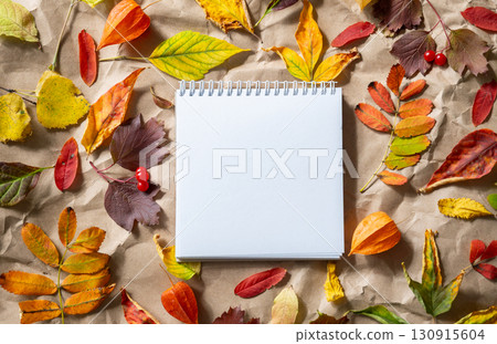 White blank spiral notebook with autumn leaves on crumpled craft paper. Fall season background with copy space for text. 130915604