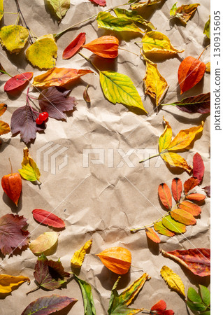 Autumn foliage frame with colorful leaves and physalis on crumpled brown paper with copy space. 130915605