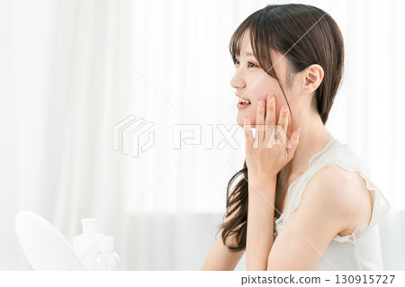 Asian woman looking in the mirror and doing skin care (moisturizing, beauty, cosmetics, skin, anti-aging) Asian woman looking in the mirror and doing skin care (moisturizing, beauty, cosmetics, skin, anti-aging) 130915727
