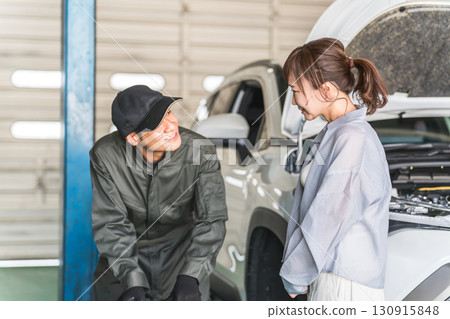 一名男性汽車修理工向一名女性司機解釋汽車輪胎 130915848