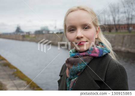 Cheerful young woman with blond hair walking outdoors, portrait Cheerful young woman with blond hair walking outdoors, portrait 130915865