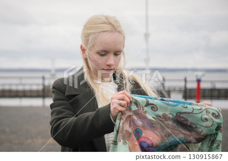 Pretty blond woman with headscarf standing outdoors 130915867