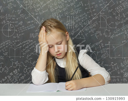 Studying child student sitting in classroom on school chalkboard background. Math education concept Studying child student sitting in classroom on school chalkboard background. Math education concept 130915993