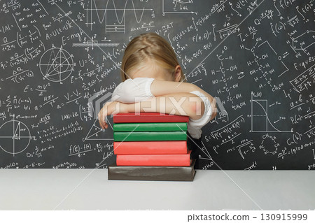 Sleeping child student sitting in classroom on chalkboard background with mathematical formulas 130915999
