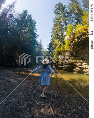 Woman Strolling by River in Forest Woman Strolling by River in Forest 130916479