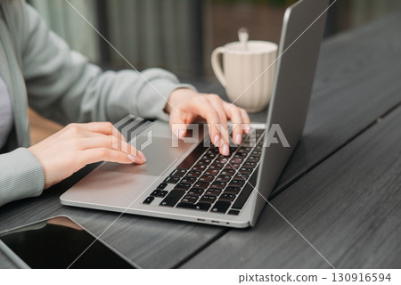 A professional woman working on her laptop outdoors. This image captures the modern concept of remote work A professional woman working on her laptop outdoors. This image captures the modern concept of remote work 130916594