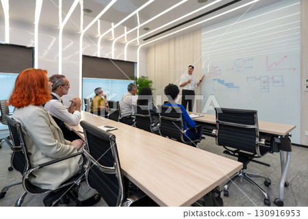 Business presentation in modern conference room showcasing data analysis and strategic planning with engaged audience participation 130916953
