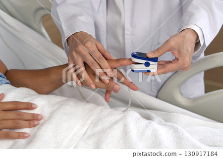 A healthcare professional is using a fingertip pulse oximeter on a patient's finger in a hospital room. This procedure is crucial for assessing respiratory health and blood oxygen level. Close up A healthcare professional is using a fingertip pulse oximeter on a patient's finger in a hospital room. This procedure is crucial for assessing respiratory health and blood oxygen level. Close up 130917184