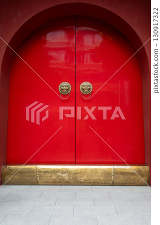 Vibrant red doors with ornate lion knockers 130917322