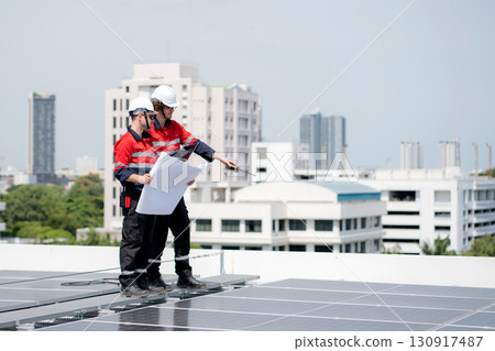 Two engineer checking solar energy system looking blueprint for planning installation solar panel. 130917487