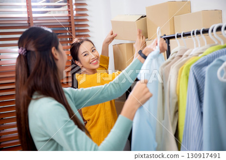 Two young asian woman arranging clothes in store for preparation delivery, seller choice clothes. 130917491