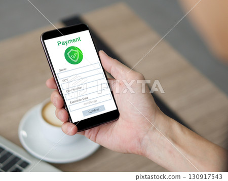 Closeup hand holding a smartphone. The phone show a payment form on its screen. Closeup hand holding a smartphone. The phone show a payment form on its screen. 130917543