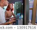 Two developer focus on coding at their desk, surrounded by multiple computer screen displaying line of code in a contemporary workspace, enhancing teamwork and creativity. 130917616