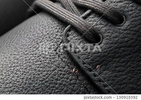 Dark leather shoe with lace-up front. Detailed view of high-quality shoe material. Ideal for elegant fashion or product shoot. 130918392