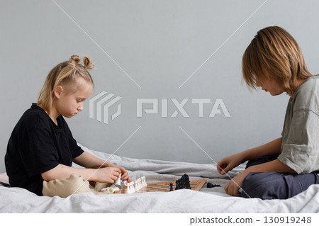 Cheerful little girl and young boy have a nice game. Sibling playing chess  130919248