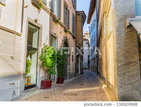 Empty narrow Italian street in Como city. Multicolor old yellow house building architecture 130920006