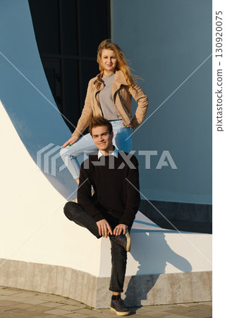 Couple poses together in urban setting with modern architecture under warm sunlight Couple poses together in urban setting with modern architecture under warm sunlight 130920075