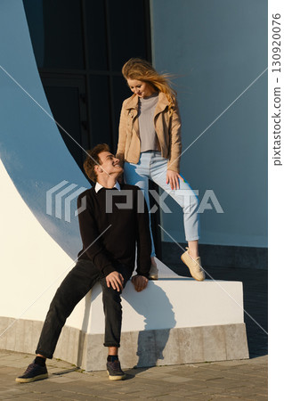 Couple enjoying a playful moment near modern architecture during a sunny day 130920076