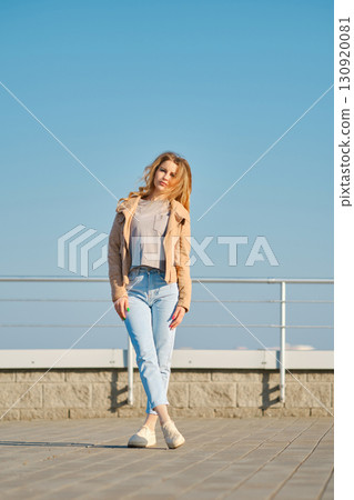 Stylish woman enjoying a sunny day at a waterfront promenade with blue sky Stylish woman enjoying a sunny day at a waterfront promenade with blue sky 130920081