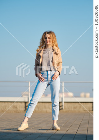 Young woman poses confidently on sunny rooftop against clear blue sky in stylish casual outfit Young woman poses confidently on sunny rooftop against clear blue sky in stylish casual outfit 130920086