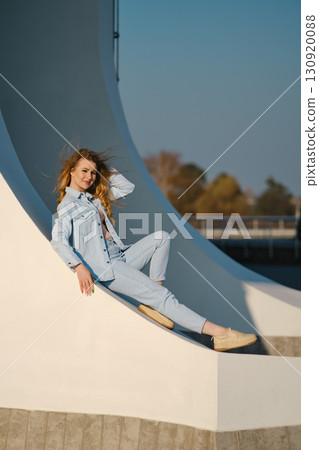Young woman relaxes gracefully on a modern architectural structure during a sunny afternoon Young woman relaxes gracefully on a modern architectural structure during a sunny afternoon 130920088