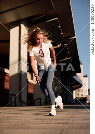 Athletic young woman sprinting outdoors in urban setting under bright sunlight Athletic young woman sprinting outdoors in urban setting under bright sunlight 130920220