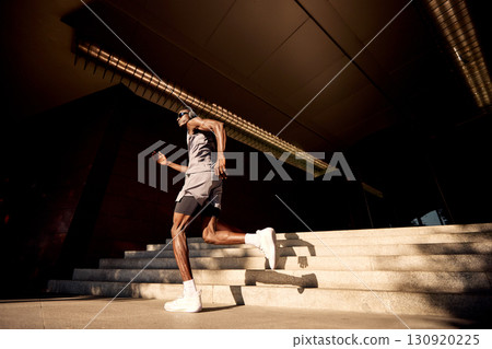 Athlete Jogging on Sunlit Steps Near a Modern Urban Building Athlete Jogging on Sunlit Steps Near a Modern Urban Building 130920225