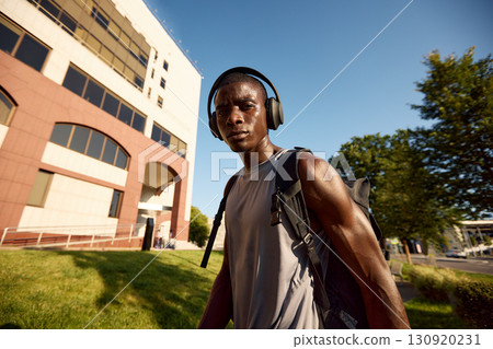 Man listening to music with headphones while walking outdoors in the city 130920231