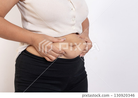 Overweight woman hand pinching excessive belly fat on gray background, Healthy concept 130920346