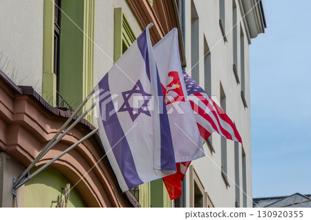 Poland, Krakow, American, Israeli, and Polish flags with an eagle's head on a facade. 130920355