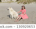 Young woman with her husky dog relaxing on the beach 130920653