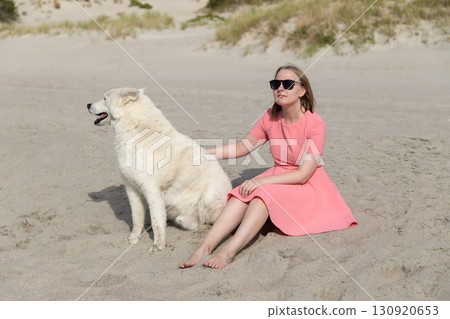 Young woman with her husky dog relaxing on the beach 130920653