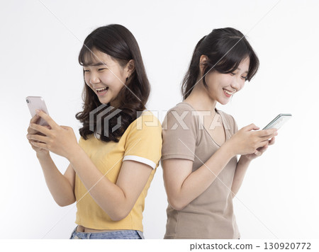 Happy Teenage girls laughing and using mobile phone 130920772