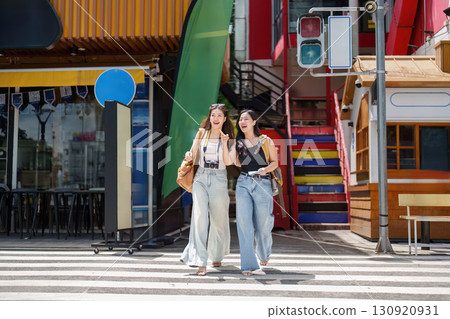 Joyful Journey. Two young women crossing a colorful street while laughing. 130920931