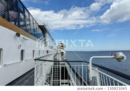 A dynamic perspective shot from the deck of a large ferry, looking out over the calm blue sea. 130921043