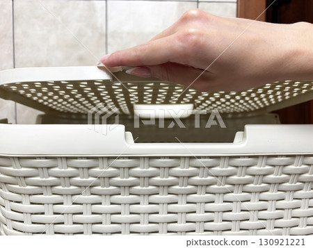 Woman hand opening laundry basket in bathroom. Household chores, laundry routine, home hygiene and cleanliness concept 130921221