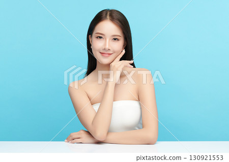 A beautiful young Asian woman with clean, fresh skin against a blue background. Skincare, facial treatment, cosmetology, beauty, and spa. An elegant portrait of an Asian woman. A beautiful young Asian woman with clean, fresh skin against a blue background. Skincare, facial treatment, cosmetology, beauty, and spa. An elegant portrait of an Asian woman. 130921553