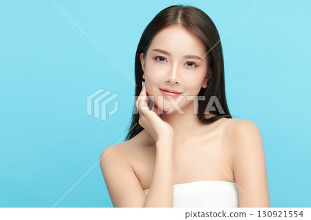 A beautiful young Asian woman with clean, fresh skin against a blue background. Skincare, facial treatment, cosmetology, beauty, and spa. An elegant portrait of an Asian woman. A beautiful young Asian woman with clean, fresh skin against a blue background. Skincare, facial treatment, cosmetology, beauty, and spa. An elegant portrait of an Asian woman. 130921554