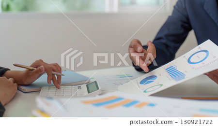 Financial Consultation. Professionals discussing budget charts and graphs in a collaborative setting. Financial Consultation. Professionals discussing budget charts and graphs in a collaborative setting. 130921722