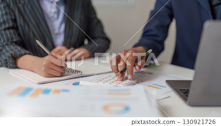 Financial Analysis. Business professionals collaborating on budget calculations using a calculator. 130921726