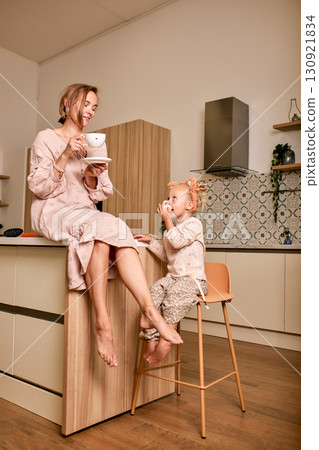 Mother and daughter enjoying a warm drink together in the kitchen Mother and daughter enjoying a warm drink together in the kitchen 130921834