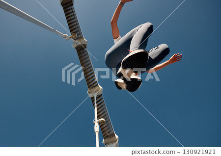Low angle view of a person jumping high under a clear blue sky 130921921
