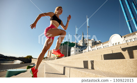 Fit woman jogging up stairs outdoors in a vibrant urban setting 130922015
