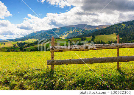 wooden fence on the grassy meadow in mountainous countryside. rural landscape of transcarpathia with rolling hill in september on a sunny day with clouds on the blue sky 130922303