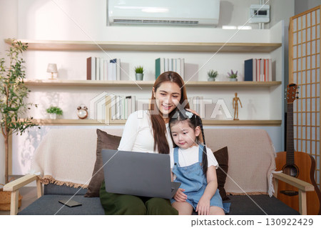 Mother and daughter sharing laughter while using a laptop 130922429
