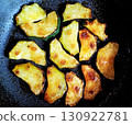 Crispy golden fried zucchini slices cooking in a black frying pan with oil, vegetarian snack food 130922781