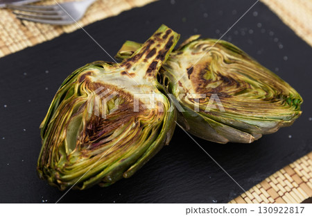 cooked fried halves artichokes on black stone board 130922817