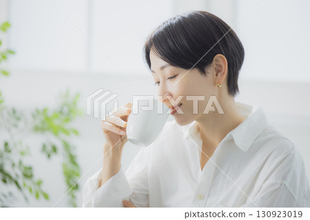 Middle woman drinking coffee in the living room Middle woman drinking coffee in the living room 130923019