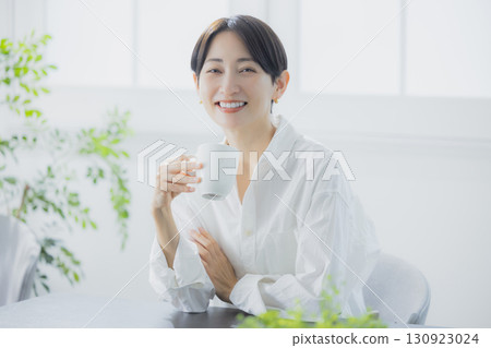 Middle woman drinking coffee in the living room Middle woman drinking coffee in the living room 130923024