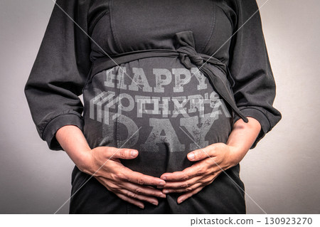 Pregnant woman with happy mothers day text on belly for maternity celebration concept 130923270